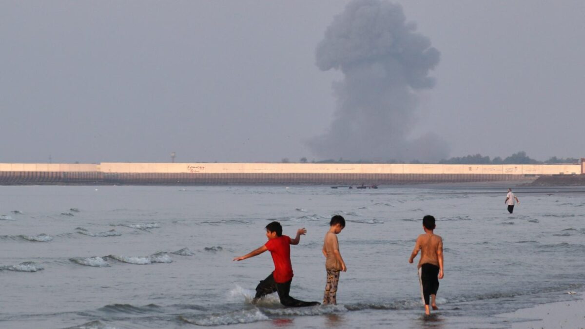 Three boys play in the waters of the Strait of Hormuz. The US and Iran each assert they control it after another heavy exchange of fire