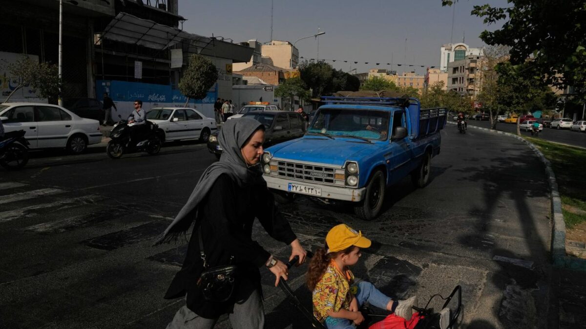 A woman crosses a street with a girl in downtown Tehran, Iran, Wednesday, July 22, 2026.