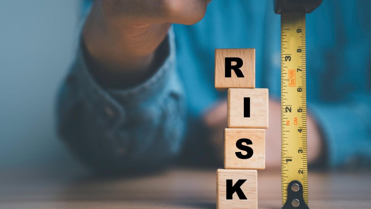 A stack of blocks spelling out risk next to a tape measure.