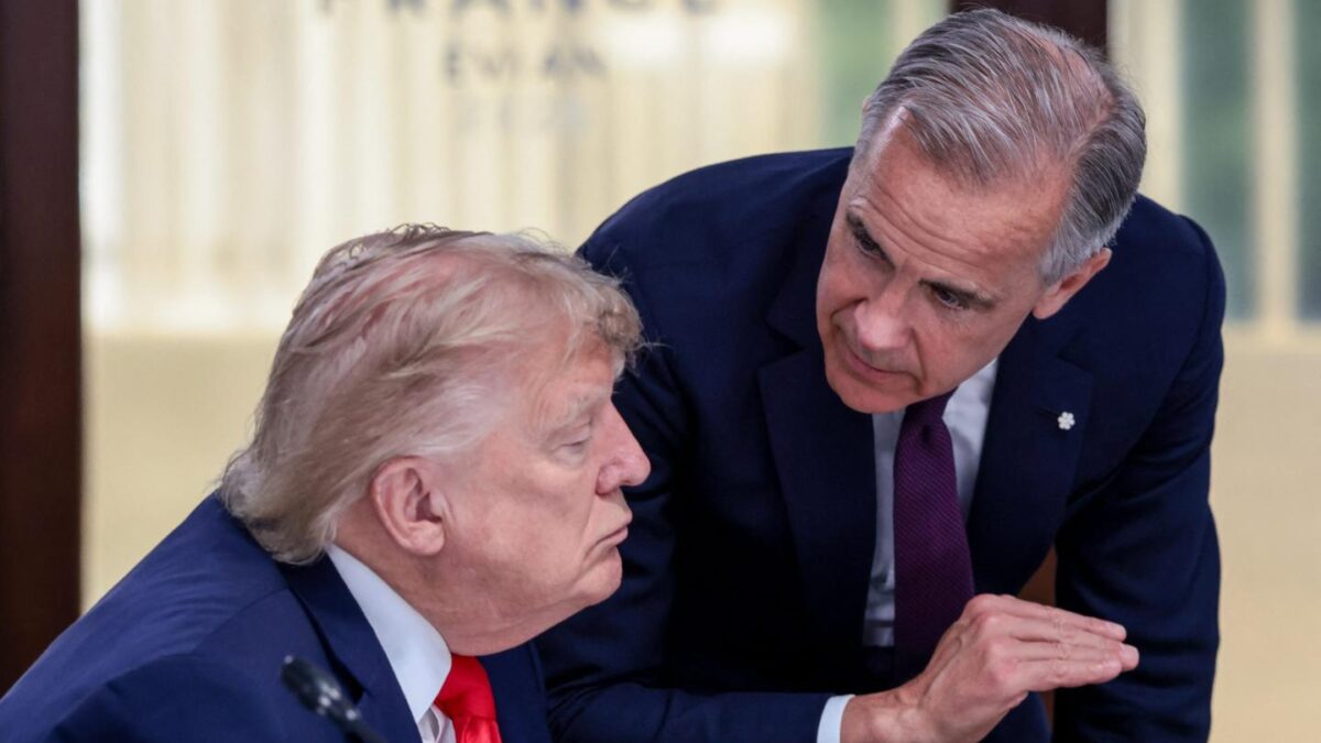 Mark Carney leans over next to Donald Trump with his hand raised.