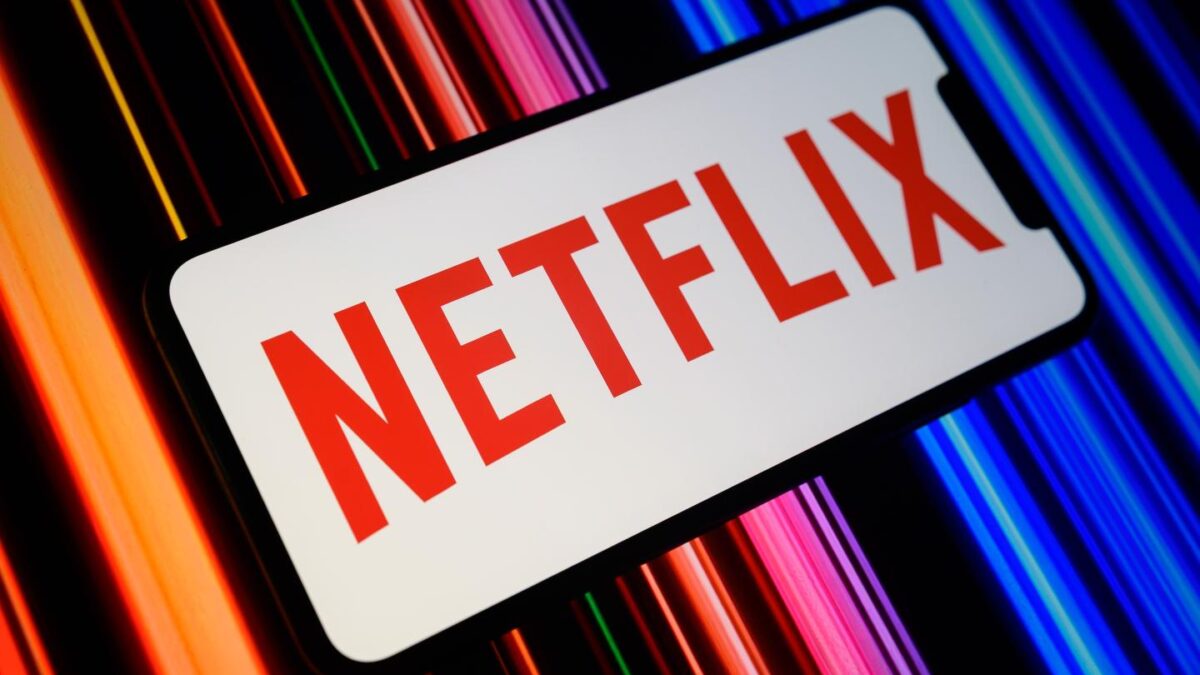 The Netflix logo is displayed on a smartphone screen featuring a color gradient in the background.