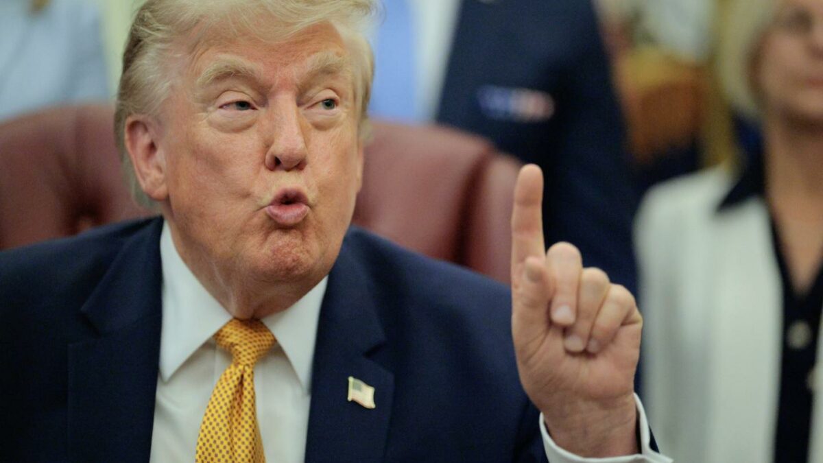Donald Trump, in the middle of speaking, holds up his hand with his pointer finger extended.