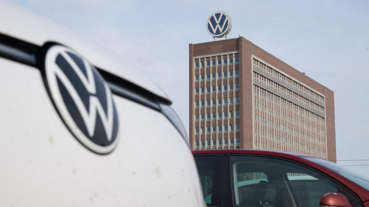 VW cars are parked in a parking lot across from the brand's skyscraper at the VW main plant.